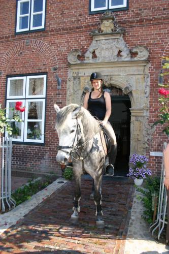 a woman riding a horse in front of a building at Gasthof Oldenwöhrden in Wöhrden