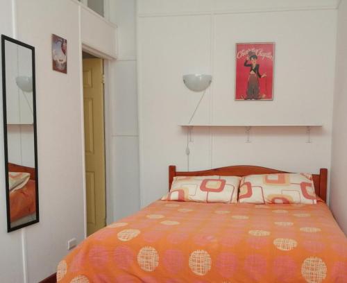 a bedroom with a bed with an orange comforter at La Otra Vista in Valparaíso
