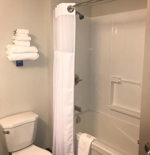 a bathroom with a shower and a toilet and towels at Travelodge by Wyndham Sydney in Sydney