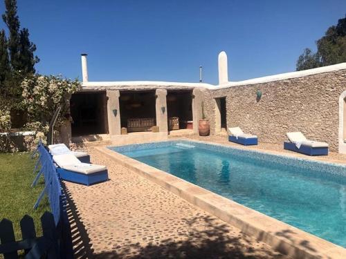 ein Swimmingpool mit Stühlen und ein Haus in der Unterkunft Comme un hameau de charme dominant l'Océan in Essaouira