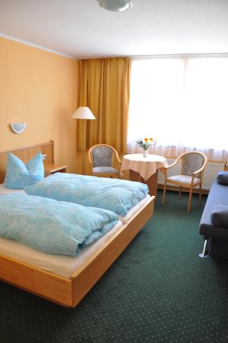 une chambre d'hôtel avec un lit, une table et des chaises dans l'établissement Pension Müritzblick, à Waren