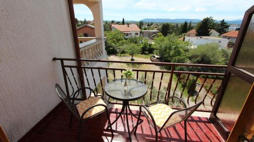 a balcony with a glass table and chairs on a balcony at Room Jelka 3 in Malinska