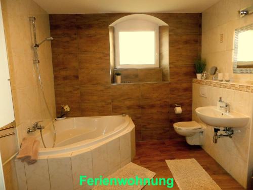 y baño con bañera, aseo y lavamanos. en Ferienwohnung Sobrigau, en Sobrigau