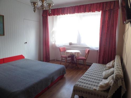 a bedroom with a bed and a table and a window at Bori Apartmanok in Hajdúszoboszló