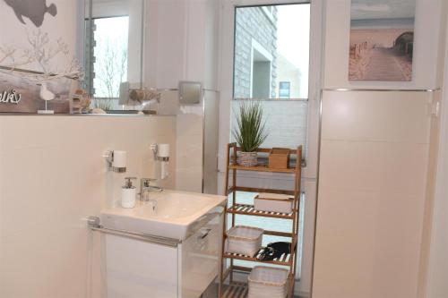 een witte badkamer met een wastafel en een spiegel bij Apartment am See, Am Alten Deich 4-6, Whg 1 24 in Dangast