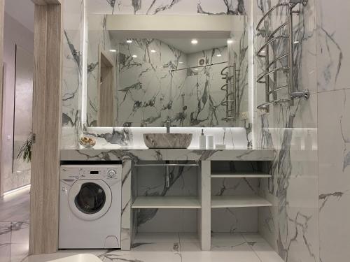 a bathroom with a sink and a washing machine at Panorama Luxury Apartment in The House with a Spire, a historical building in the city centre in Kharkiv
