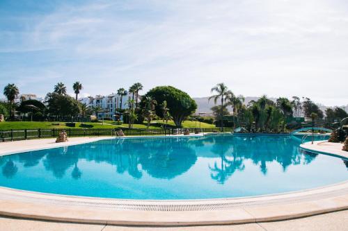 a large blue pool with palm trees and buildings in the background at APARTAMENTO 1º LINEA DE PLAYA ZAHARA DE LOS ATUNES in Zahara de los Atunes