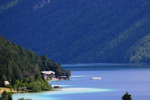 a large body of water with a house and trees at Der Ronacherfels in Weissensee