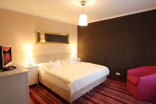 a hotel room with a bed and a red chair at Der Ronacherfels in Weissensee