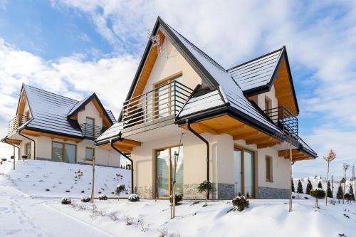 a house with snow on the ground at Domki Sówka in Dursztyn