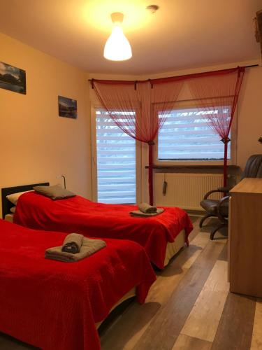 sypialnia z 2 czerwonymi łóżkami i oknem w obiekcie Mieszkanie u Tomka INPIW02 w mieście Piwniczna