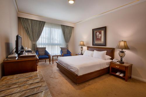 a hotel room with a bed and a desk and a television at Amman International Hotel in Amman