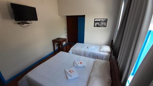 a hotel room with two beds and a flat screen tv at Hotel Nossa Senhora Aparecida in Ouro Preto