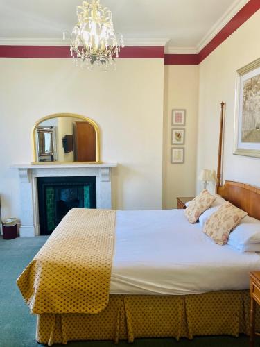 a bedroom with a large bed and a chandelier at Canterbury Hotel Cottages and Apartment's in Canterbury