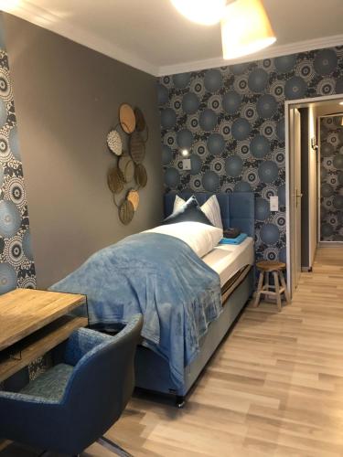 a bedroom with a blue bed and a chair at Pension Ottenheide in Schloß Holte-Stukenbrock