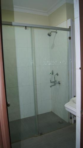 a shower with a glass door next to a sink at Hotel MGM Grand in Srikalahasti