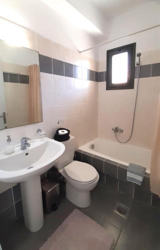 a bathroom with a sink and a toilet and a tub at VILLA ANDRONIKI in Fiskardo
