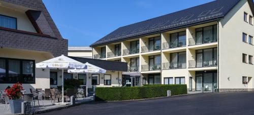 a hotel with tables and chairs in front of it at Hotel Haus Tiefenbach in Bullange