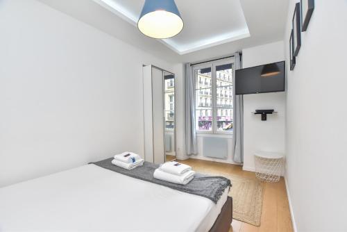 a white bedroom with a bed and a window at CMG Louvre Rivoli - Châtelet in Paris