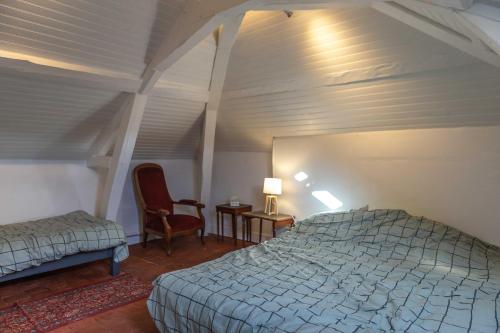 een slaapkamer met een bed en een stoel in een kamer bij Chambre d'Hôtes Les Jardins de Marie, SCI Charles III in Bernay