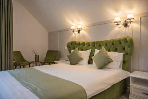 Schlafzimmer mit einem großen Bett mit einem grünen Kopfteil in der Unterkunft Boga Rooms in Sinaia