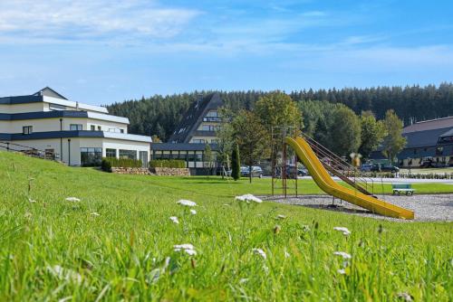 a playground with a slide in a grassy field at Hotel Haus Tiefenbach in Bullange