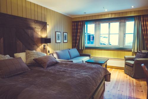 a bedroom with a bed and a couch and a chair at Gudbrandsgard Hotel in Kvitfjell