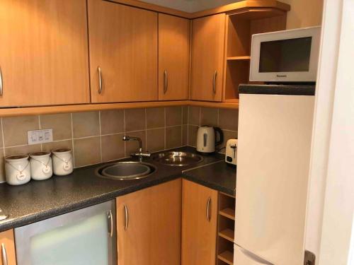 uma cozinha com armários de madeira, um lavatório e um micro-ondas em Lovely 1-Bed House in Stirling em Stirling