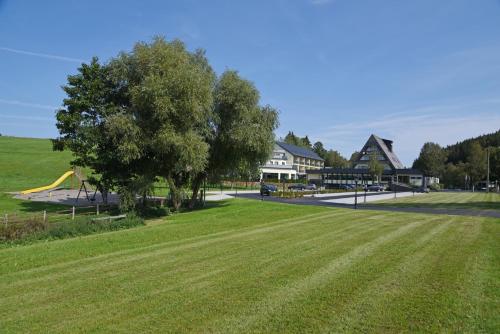 a park with a green field and a playground at Hotel Haus Tiefenbach in Bullange