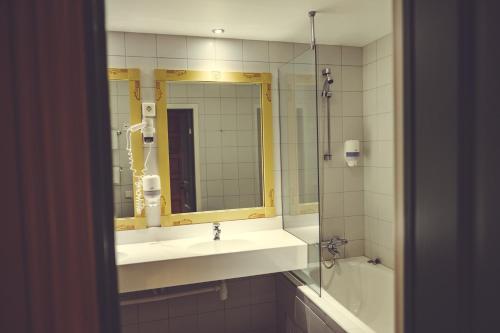 een badkamer met een wastafel, een spiegel en een bad bij Gudbrandsgard Hotel in Kvitfjell
