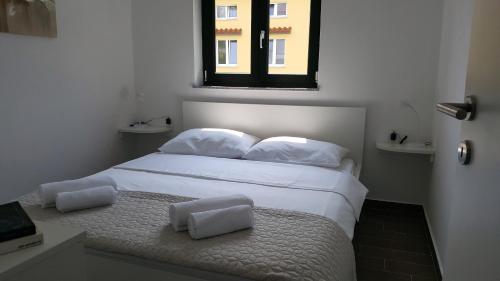 a bedroom with a bed with two pillows and a window at Apartments ARTEMIS in Baška