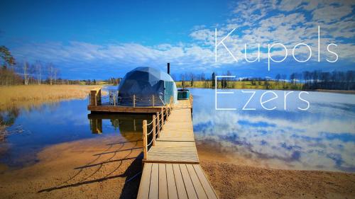 a wooden dock with a domed house on a lake at Glamping DiDille in Drusti