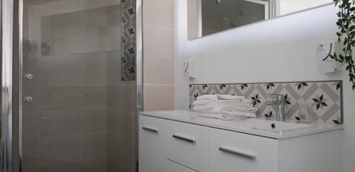 biała łazienka z umywalką i prysznicem w obiekcie Hotel-Restaurant Du Port w mieście Mèze