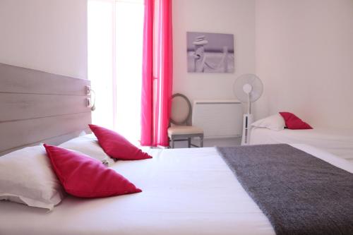um quarto com 2 camas com almofadas vermelhas e brancas em Hotel-Restaurant Du Port em Mèze