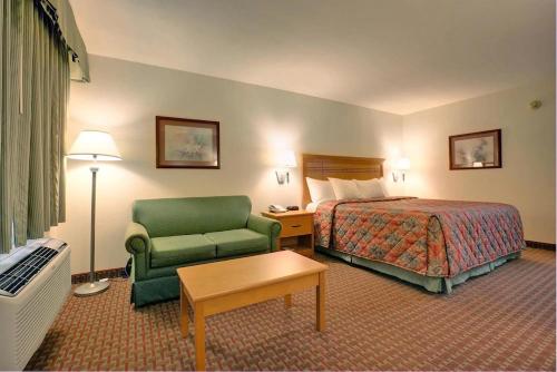 Habitación de hotel con cama y silla verde en Scottish Inns en DeSoto