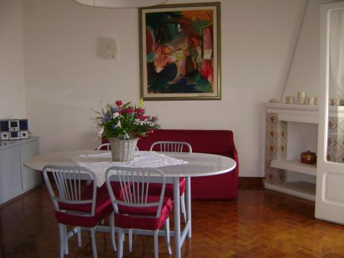 una mesa de comedor con sillas y un jarrón de flores en Il Ciclamino, en Alberobello