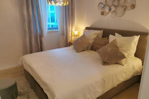 uma cama com lençóis brancos e almofadas num quarto em Magnifique F3, 75m² avec Parking privé et Terrasse em Estrasburgo