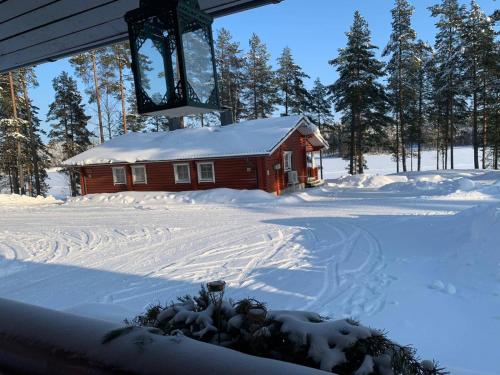 a small red cabin in the snow with trees at Pankkotupa 8B in Punkaharju