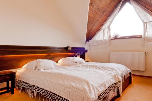 a bedroom with a large bed and two windows at Pensiunea Inima Bucovinei in Frasin