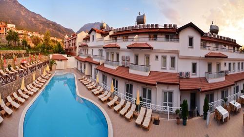 un hôtel avec une piscine en face d'un bâtiment dans l'établissement Konfor Suite Otel, à Ölüdeniz