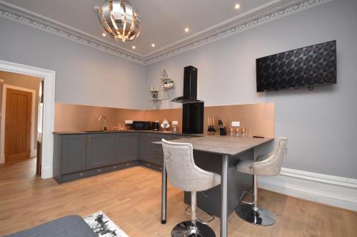 a kitchen with a counter and two stools at Signature Apartments in Fraserburgh