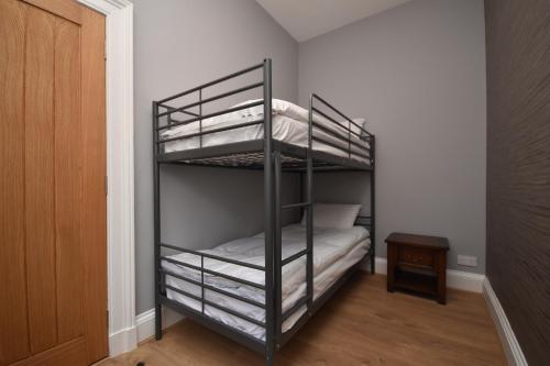 a bedroom with a bunk bed with white sheets at Signature Apartments in Fraserburgh