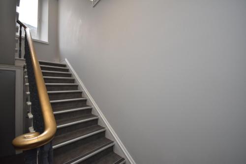 a set of stairs in a building with a gold handrail at Signature Apartments in Fraserburgh