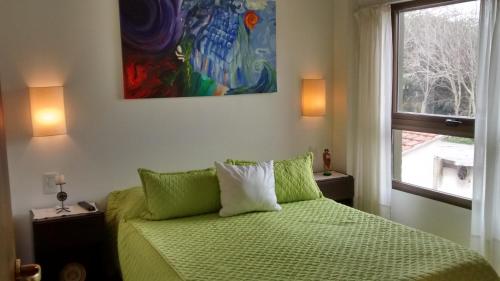 een slaapkamer met een groen bed en een schilderij aan de muur bij Reflejo de Mar in Villa Gesell
