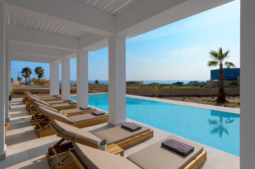a row of lounge chairs next to a swimming pool at Seawater Villa in Lachania