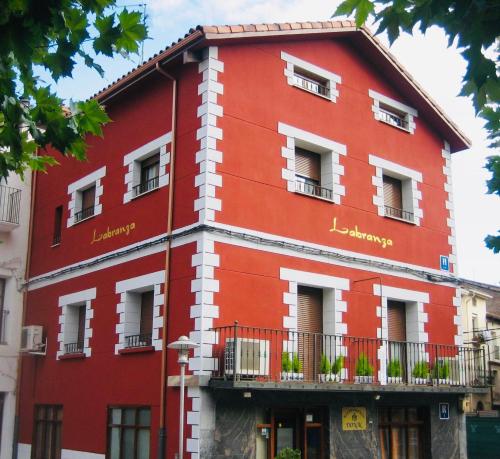 un edificio rojo con ventanas y balcones en Hostal Labranza, en Fuenmayor