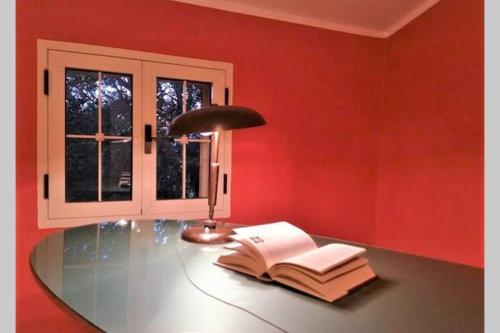 una mesa de cristal con una lámpara y un libro abierto en Big relax apartment with swimming pool and a peaceful garden in a private villa en Sestu
