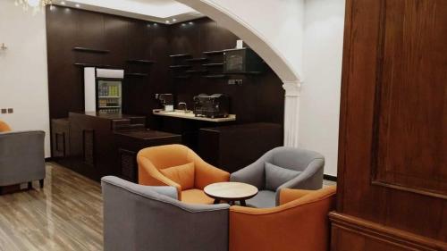 a lobby with chairs and a table and a kitchen at Ostrava Suites in Abha