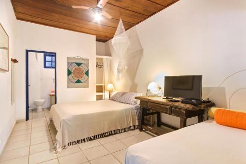 a bedroom with two beds and a desk with a television at Residence Picinguaba in Picinguaba