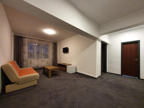 una stanza con una sedia, un tavolo e una porta di Hotel Petroshani srl a Petroşani
